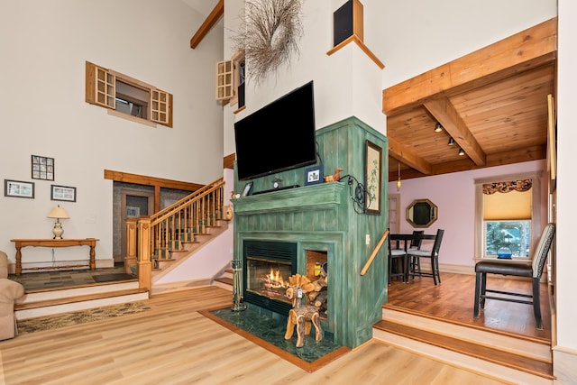 living room featuring beam ceiling, wood-type flooring, a high ceiling, and wood ceiling