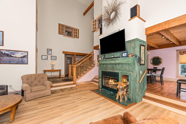 living room featuring beamed ceiling, a high ceiling, and hardwood / wood-style flooring