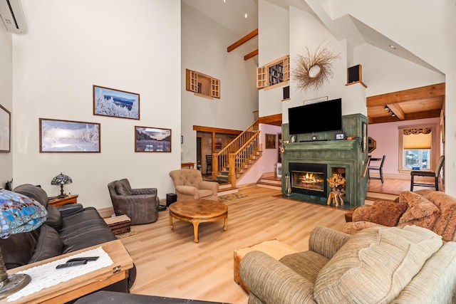 living room featuring a wall unit AC, hardwood / wood-style floors, high vaulted ceiling, and beamed ceiling