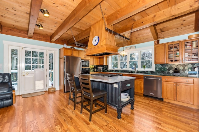 kitchen with a center island, stainless steel appliances, light hardwood / wood-style flooring, beamed ceiling, and a breakfast bar