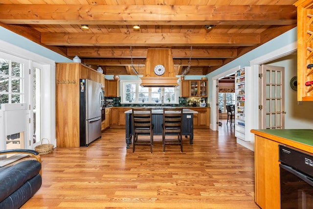 kitchen featuring stainless steel fridge, light hardwood / wood-style floors, beam ceiling, and wood ceiling