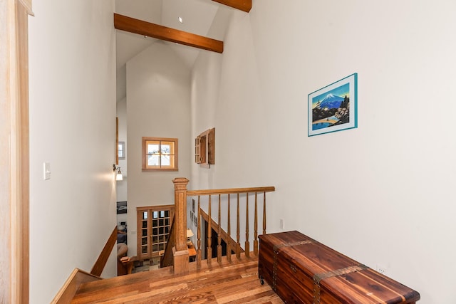 stairway featuring hardwood / wood-style flooring, beam ceiling, and high vaulted ceiling