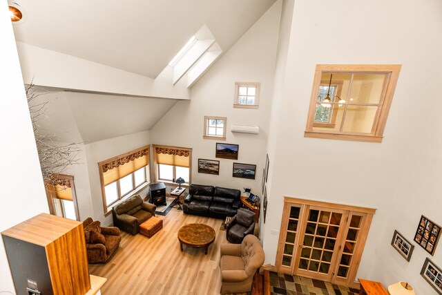 living room featuring a wall mounted AC, hardwood / wood-style floors, high vaulted ceiling, and a wealth of natural light