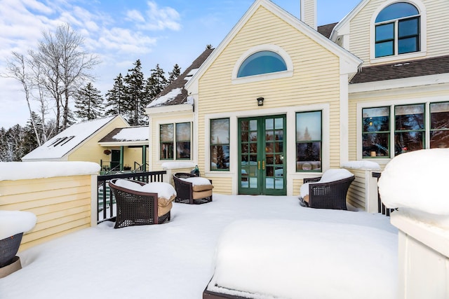 snow covered rear of property with french doors