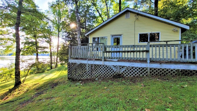 rear view of property featuring a deck with water view and a yard