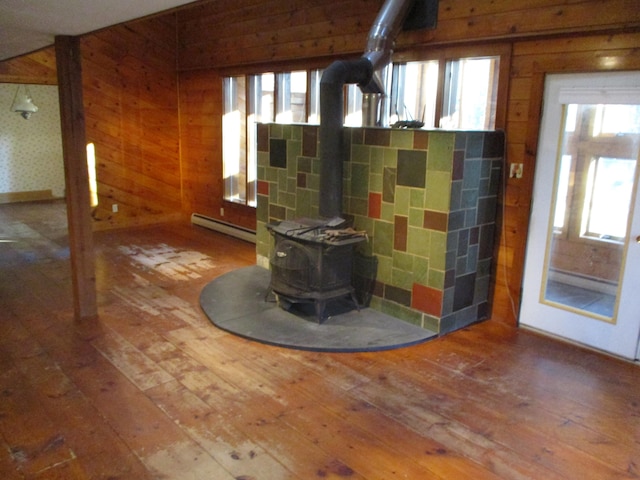 interior space featuring a wood stove, wooden walls, plenty of natural light, and wood-type flooring