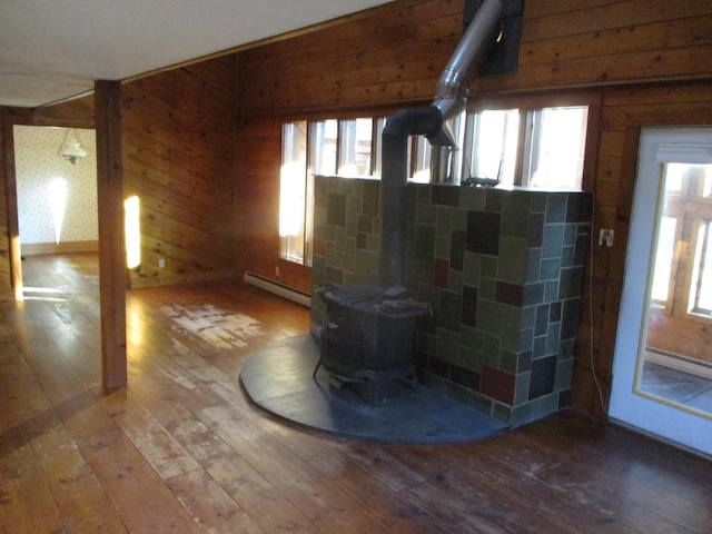 interior space featuring wooden walls, hardwood / wood-style flooring, a wood stove, and a baseboard heating unit