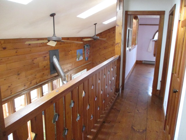 corridor with wooden walls, dark hardwood / wood-style flooring, and lofted ceiling with skylight