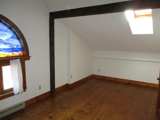 bonus room featuring dark hardwood / wood-style flooring, baseboard heating, and vaulted ceiling with skylight