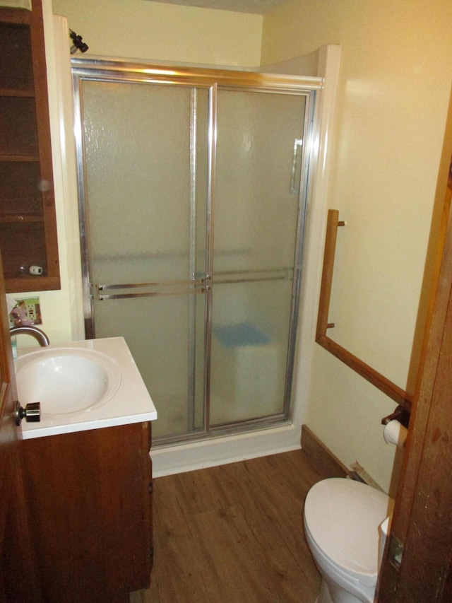 bathroom featuring vanity, hardwood / wood-style flooring, toilet, and an enclosed shower