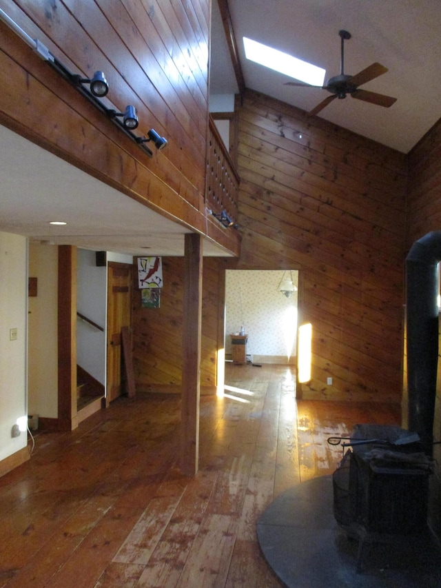 living room featuring hardwood / wood-style flooring, ceiling fan, a wood stove, and wooden walls