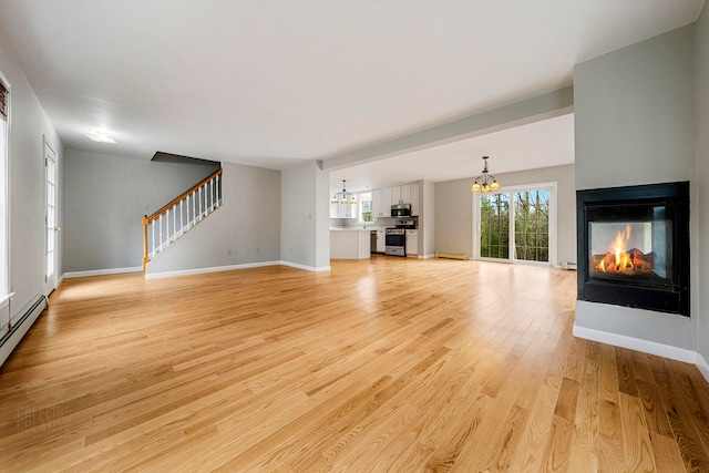 unfurnished living room with a multi sided fireplace, light hardwood / wood-style floors, an inviting chandelier, and baseboard heating