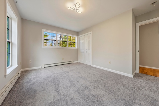 unfurnished bedroom with a closet, carpet floors, and a baseboard heating unit