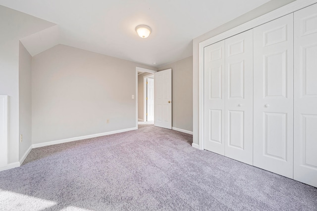 unfurnished bedroom with a closet, carpet floors, and lofted ceiling