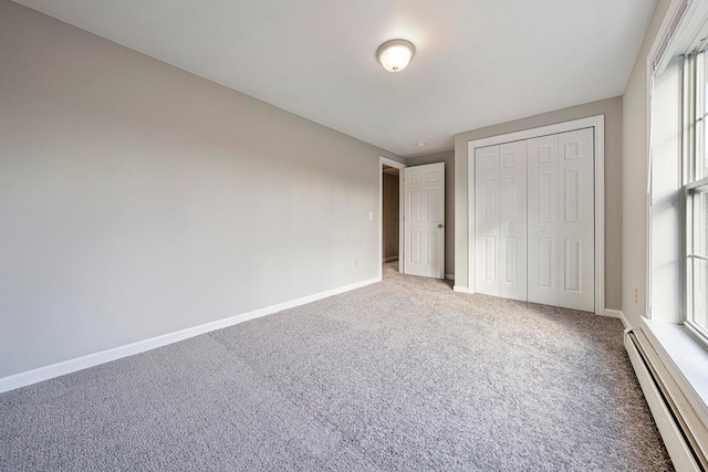 unfurnished bedroom featuring carpet flooring, baseboard heating, and a closet