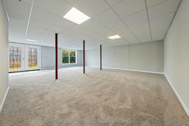 basement featuring carpet, a drop ceiling, and french doors