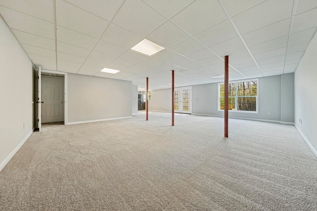 basement with a paneled ceiling and light colored carpet