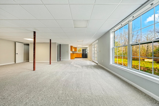 basement featuring carpet, a paneled ceiling, and black fridge