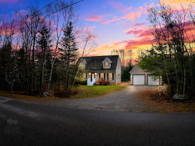 cape cod home featuring an outbuilding and a garage