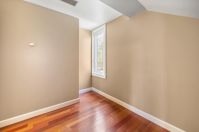 empty room featuring hardwood / wood-style floors and vaulted ceiling