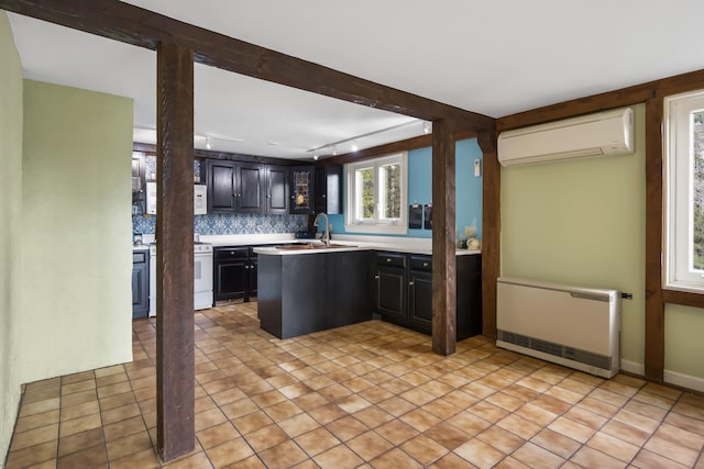 kitchen featuring sink, a wall mounted air conditioner, backsplash, heating unit, and track lighting