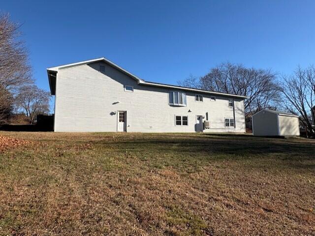 back of house featuring a lawn and a storage unit