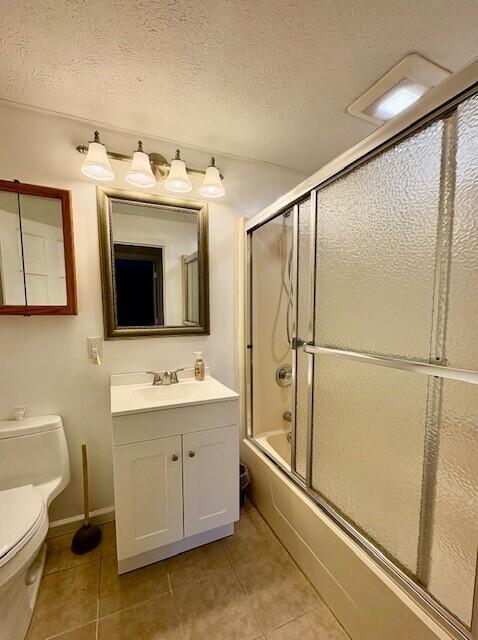 full bathroom with vanity, toilet, shower / bath combination with glass door, and a textured ceiling