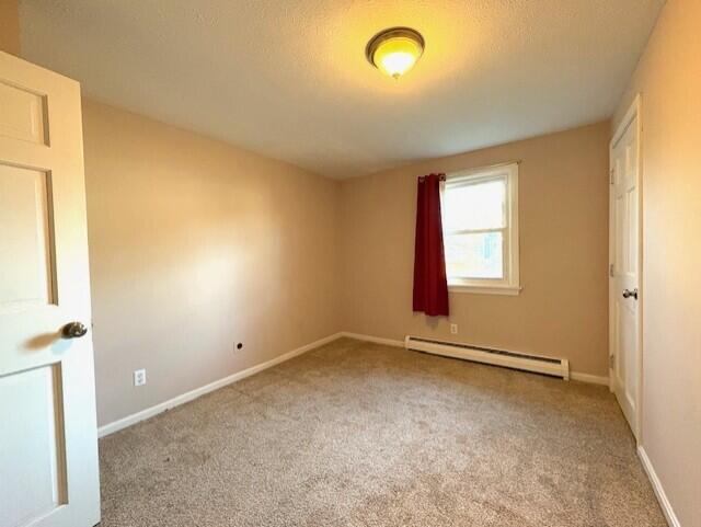 carpeted spare room featuring baseboard heating