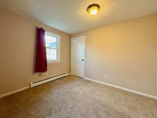 spare room with a baseboard radiator and carpet flooring