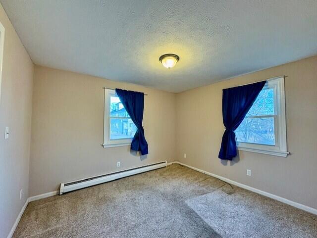 unfurnished room with a baseboard radiator, carpet, and a textured ceiling