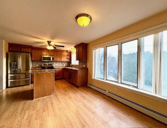 kitchen with a baseboard radiator, a center island, plenty of natural light, and appliances with stainless steel finishes