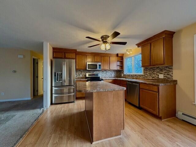 kitchen featuring tasteful backsplash, stainless steel appliances, a center island, and baseboard heating