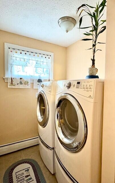 laundry room featuring a baseboard radiator, tile patterned floors, a textured ceiling, and washing machine and dryer