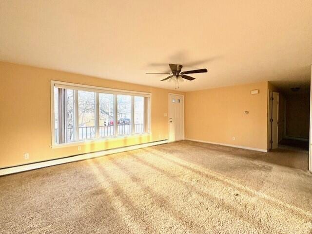 empty room with baseboard heating, ceiling fan, and carpet