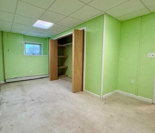 unfurnished bedroom with a drop ceiling and baseboard heating