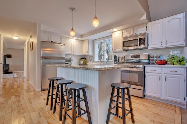 kitchen featuring white cabinets, a kitchen breakfast bar, stainless steel appliances, and light hardwood / wood-style flooring