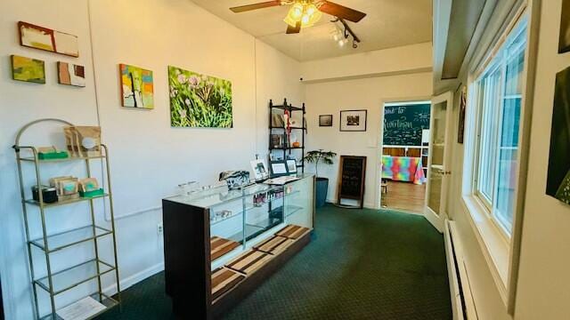 carpeted home office featuring baseboard heating and ceiling fan