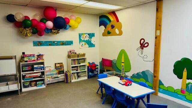 playroom featuring a paneled ceiling and concrete floors