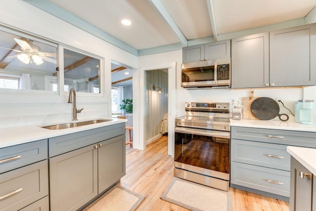 kitchen with stainless steel appliances, a wealth of natural light, gray cabinetry, and sink