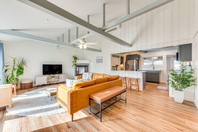 living room with beam ceiling, light wood-type flooring, high vaulted ceiling, and ceiling fan