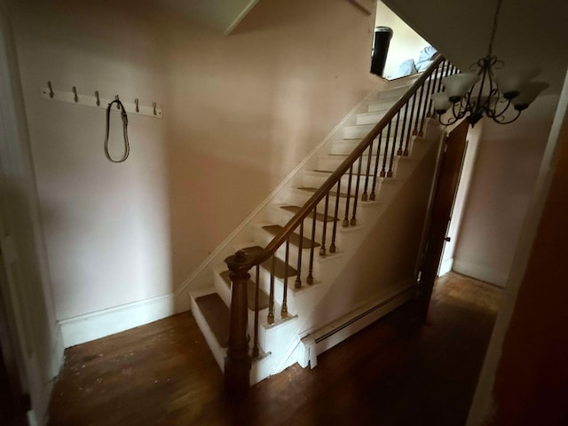 stairway with hardwood / wood-style floors, a chandelier, and a baseboard radiator