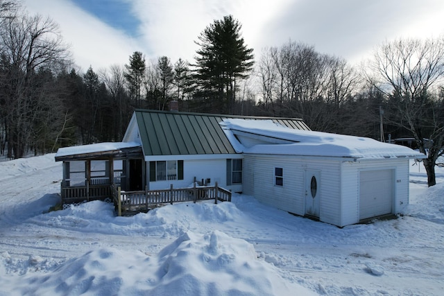 exterior space featuring a standing seam roof, a chimney, a garage, a deck, and metal roof