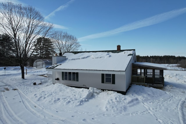 snow covered back of property with a chimney