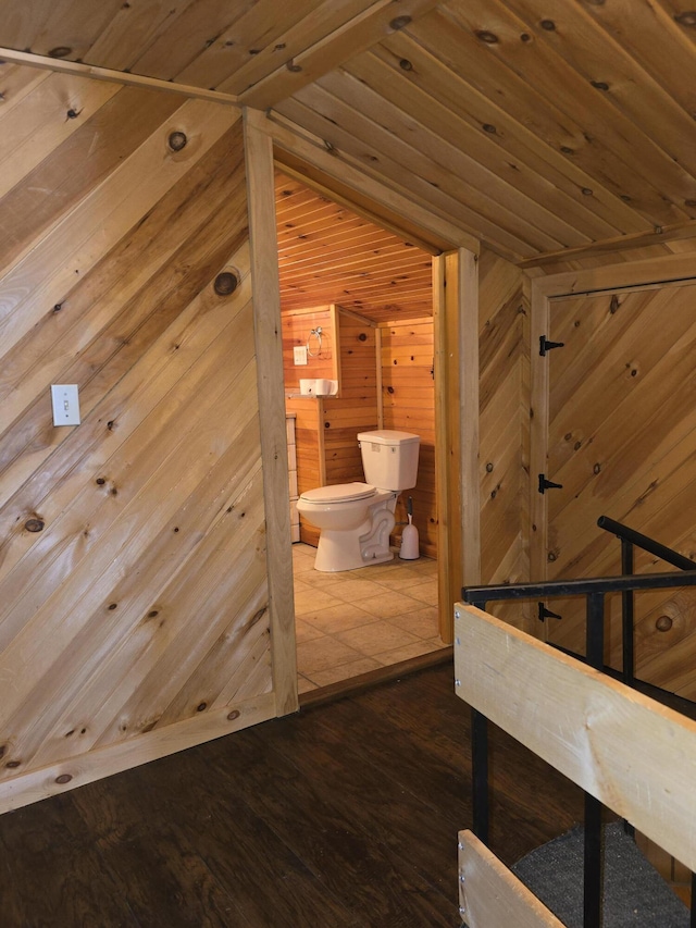 hallway with an upstairs landing, wood walls, wooden ceiling, and wood finished floors