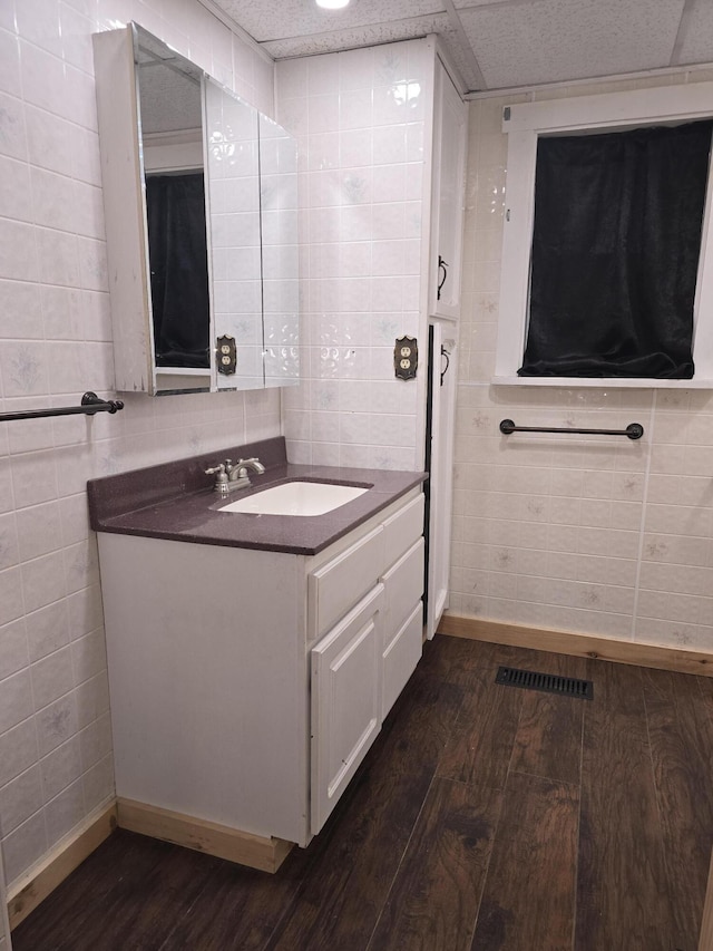 bathroom with vanity, tile walls, wood finished floors, and baseboards