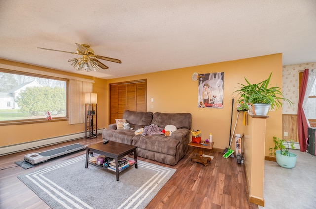 living room featuring hardwood / wood-style flooring, ceiling fan, baseboard heating, and a textured ceiling