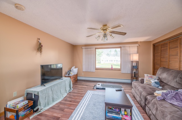 living room with a textured ceiling, a baseboard radiator, light hardwood / wood-style flooring, and ceiling fan