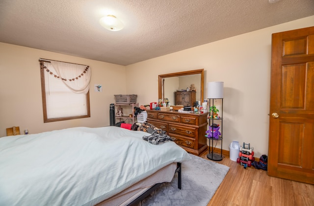 bedroom featuring a textured ceiling and light hardwood / wood-style floors