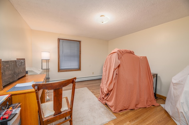 office area with a textured ceiling, light hardwood / wood-style floors, and baseboard heating