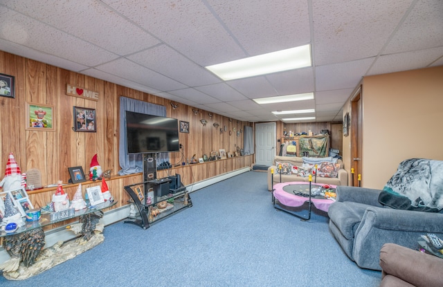 carpeted living room featuring a paneled ceiling and wooden walls